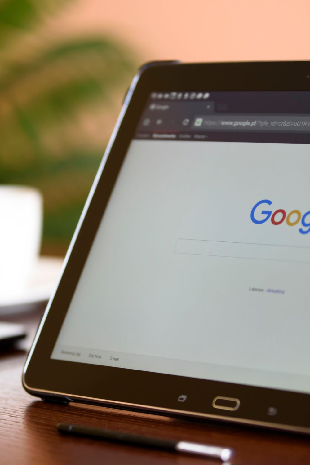 Tablet displaying Google search page on a wooden surface with a blurred background