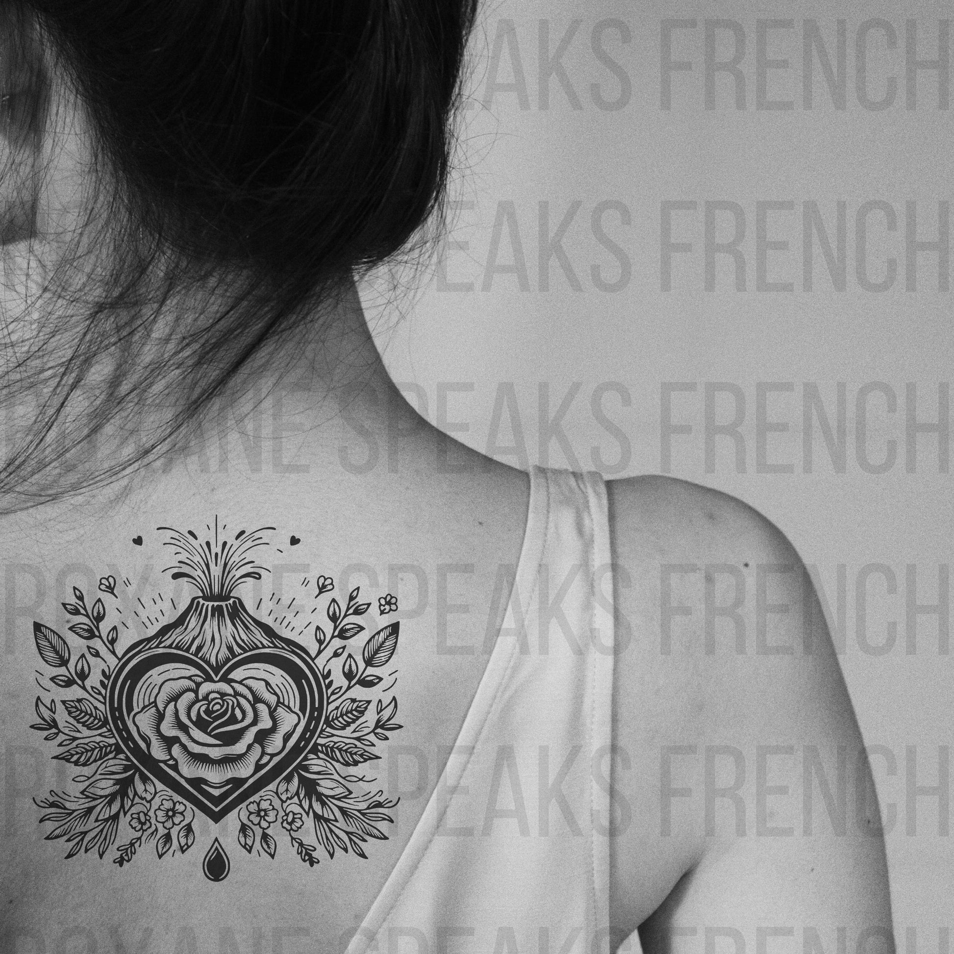 A black and white image of a woman's back with a temporary tattoo featuring a volcano erupting above a heart with a rose inside. The intricate design is surrounded by leaves and flowers, creating a striking visual effect. 